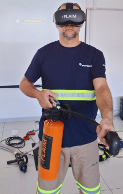 Man demonstrating FLAIM WSF. He is wearing the FLAIM Trainer headset on his face and holding the simulated fire extinguisher in his hand.